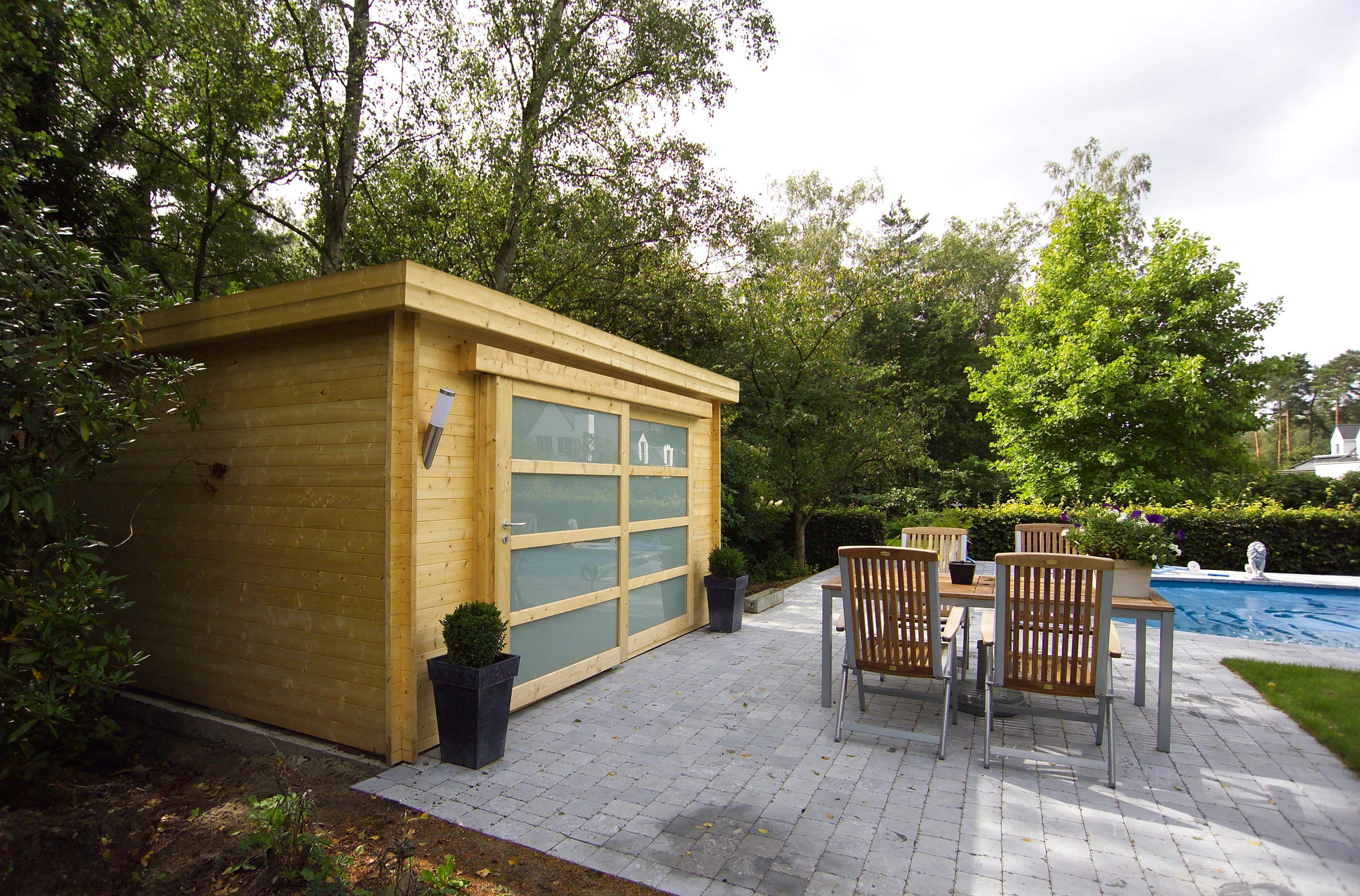 Abri de jardin moderne toit plat en bois avec portes vitrées, installé en bordure de piscine à Compiègne — Colver