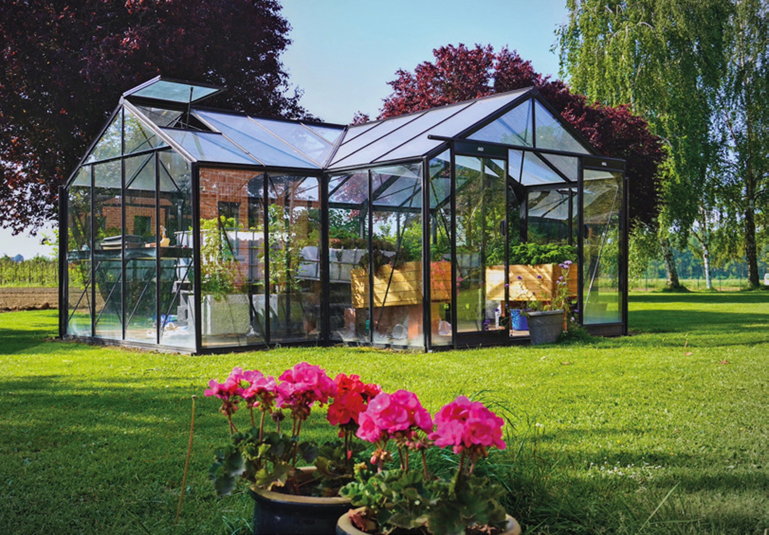 Grande serre en verre et aluminium noir avec double nef et ouvertures de toit, posée sur pelouse à Roye — Colver