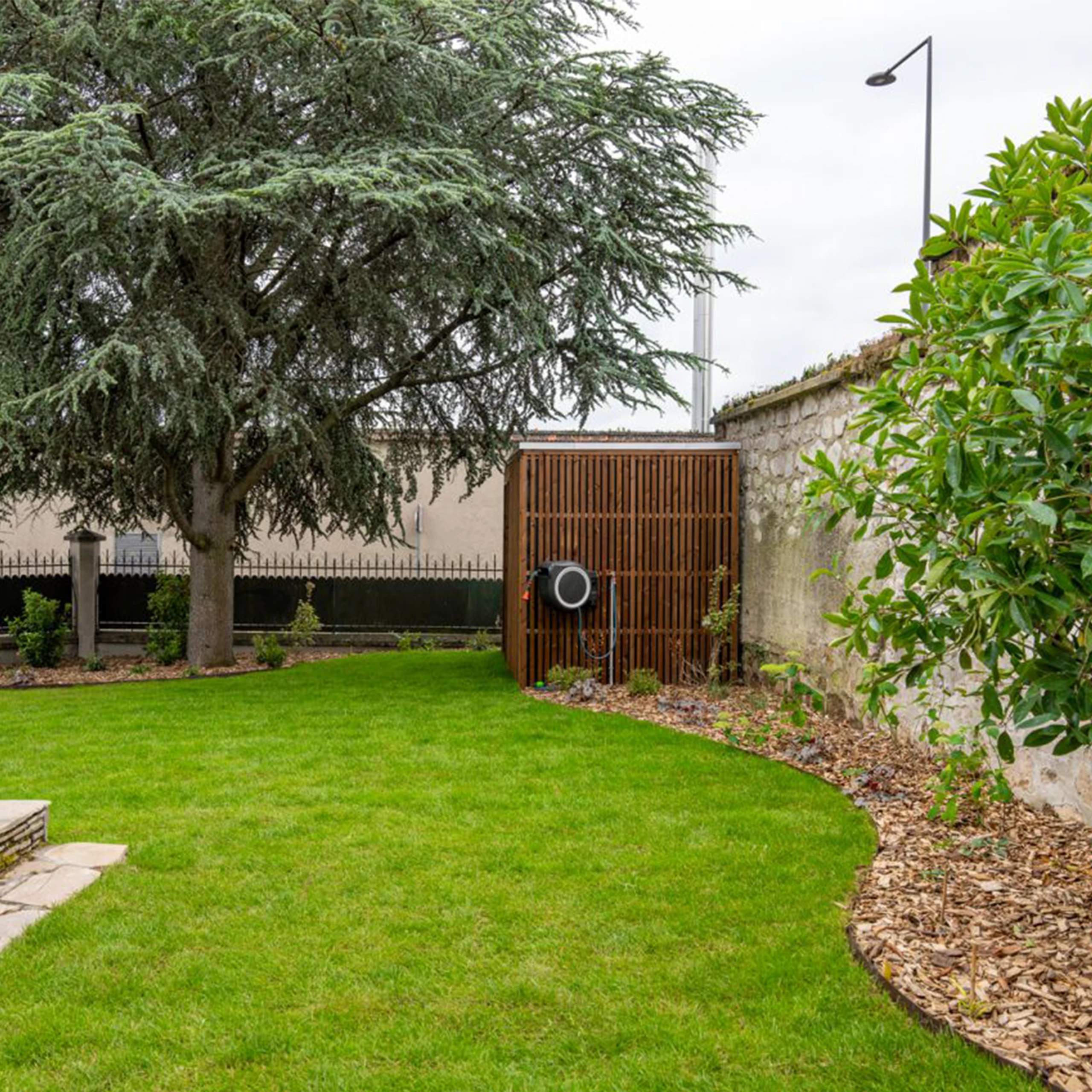 Claustra bois vertical intégré dans un jardin paysager avec pelouse soignée et massif de plantes à Soissons — Colver