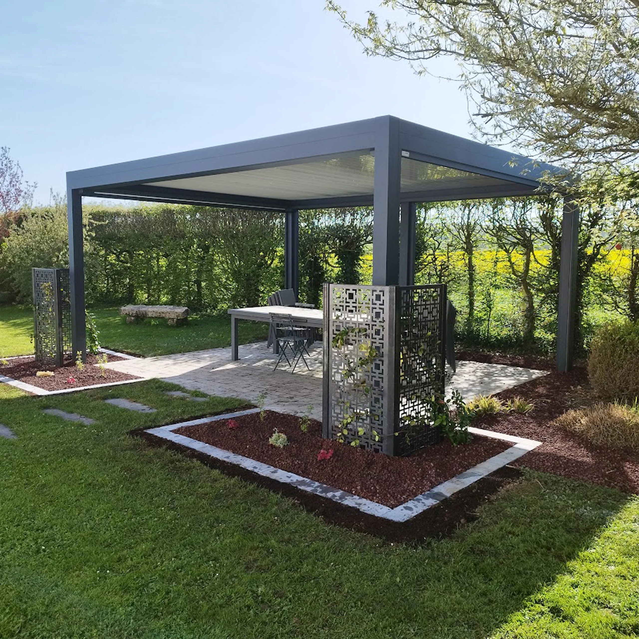 Pergola aluminium bioclimatique à lames orientables avec claustra décoratif et massifs paysagers à Roye — Colver