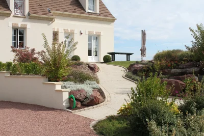 Allée en gravier stabilisé avec massifs fleuris et rochers décoratifs devant maison bourgeoise — paysagiste Oise