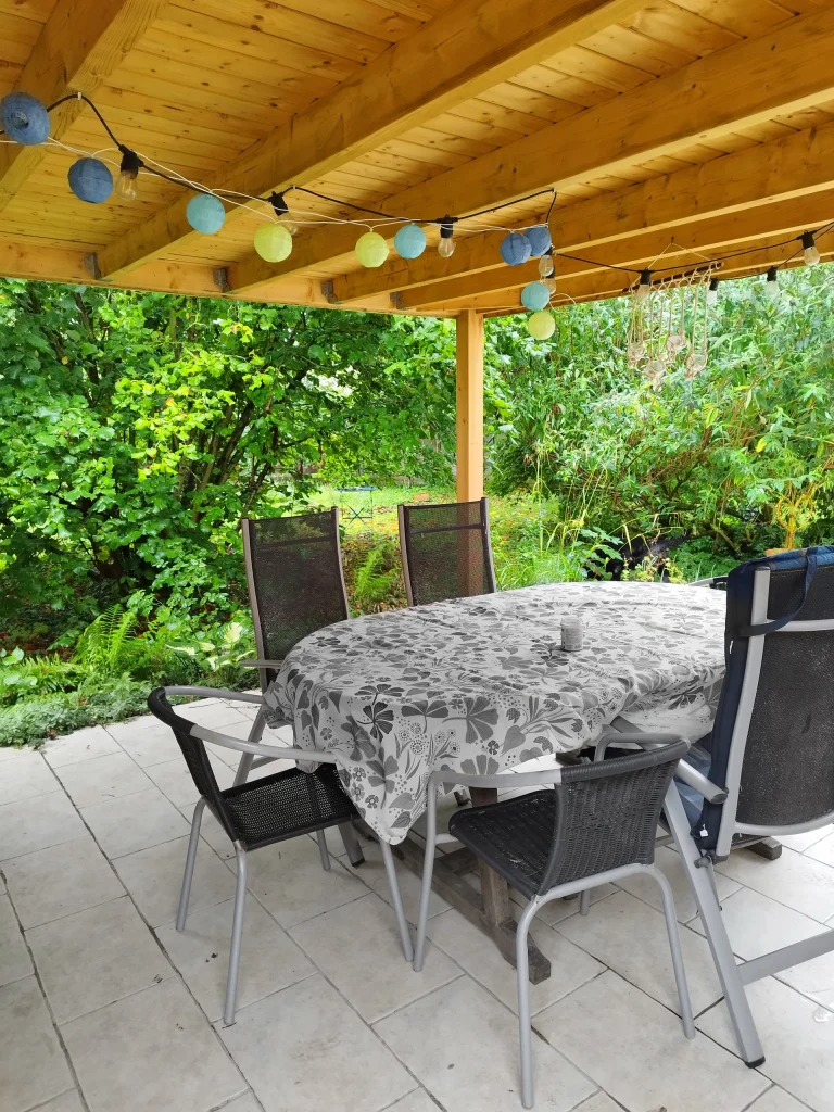 Pergola bois avec table de repas et guirlandes lumineuses sur terrasse carrelée — Compiègne, Oise — Colver