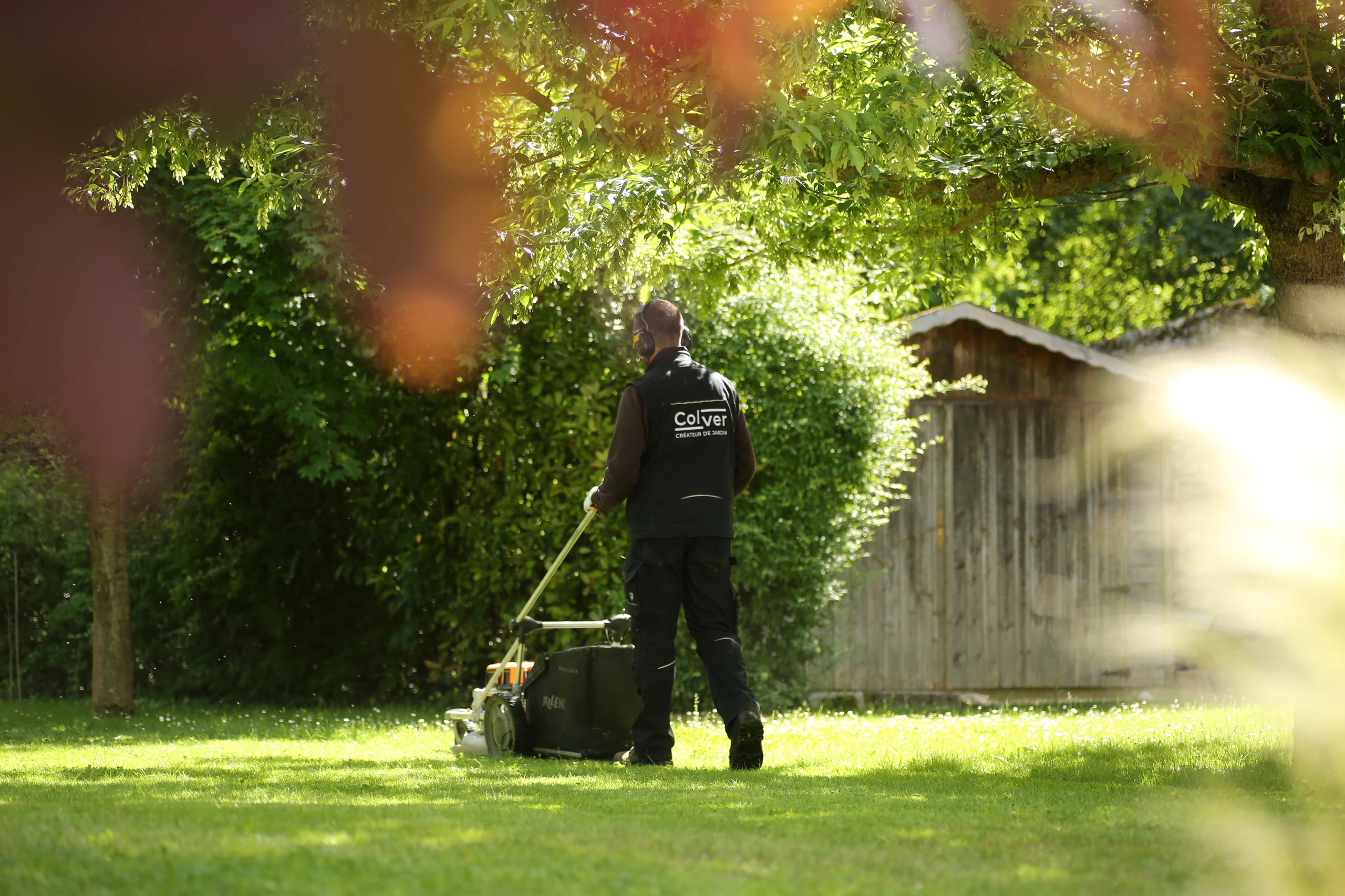 Jardinier Colver tondant une pelouse dans un jardin arboré et lumineux — Compiègne, Oise