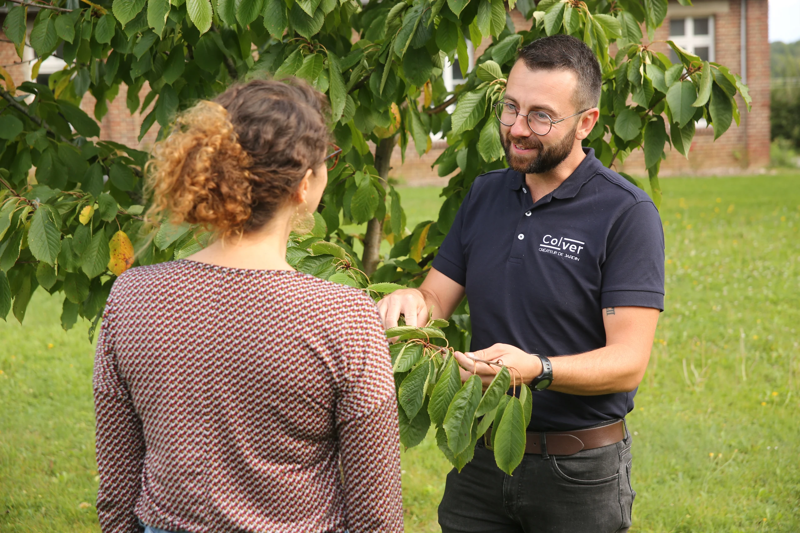 Conseiller Colver présentant les soins d'un cerisier à une cliente dans un jardin — Noyon, Oise