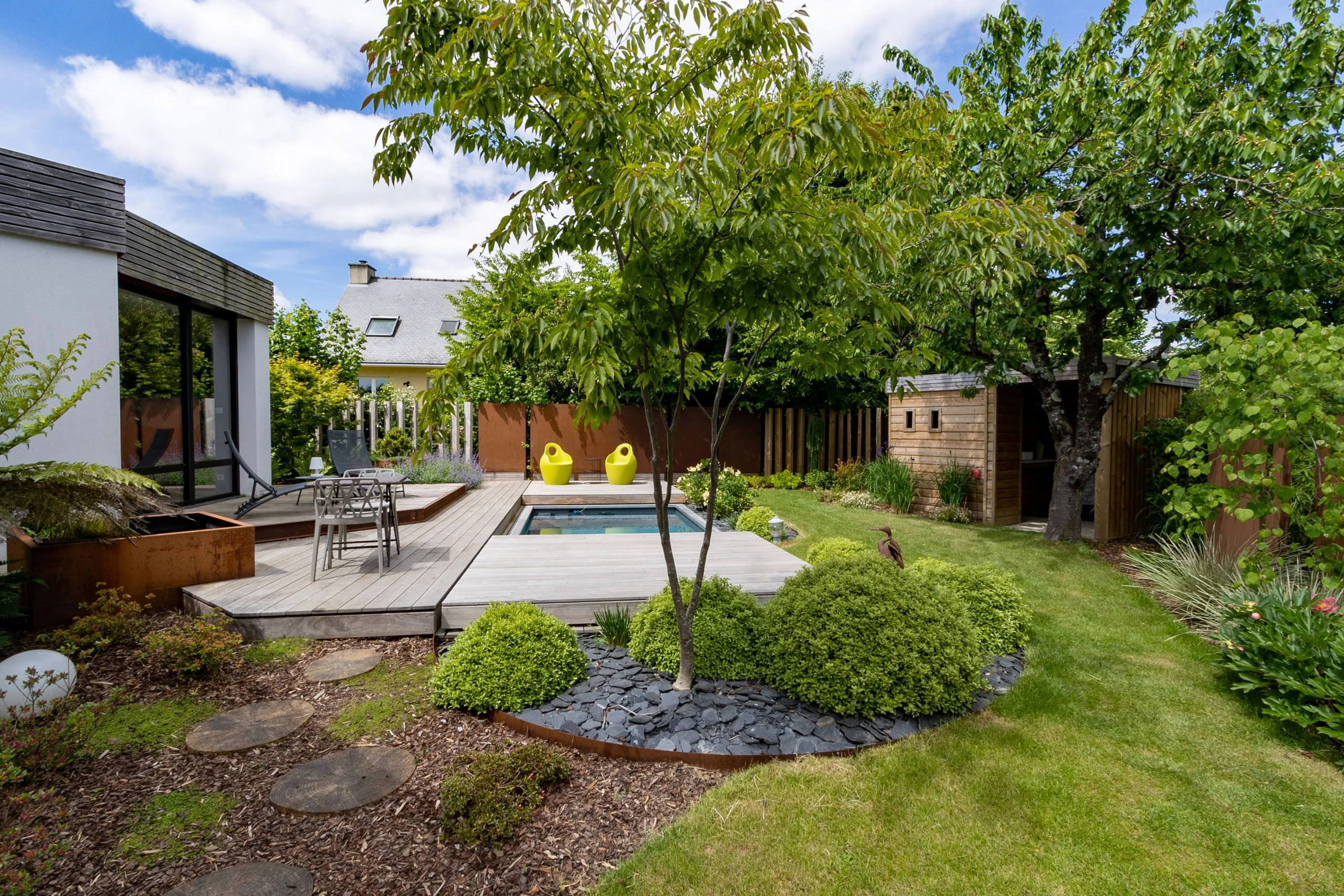 Spa de nage intégré dans un jardin paysager avec terrasse composite, bacs en acier corten et arbres à Soissons — Colver