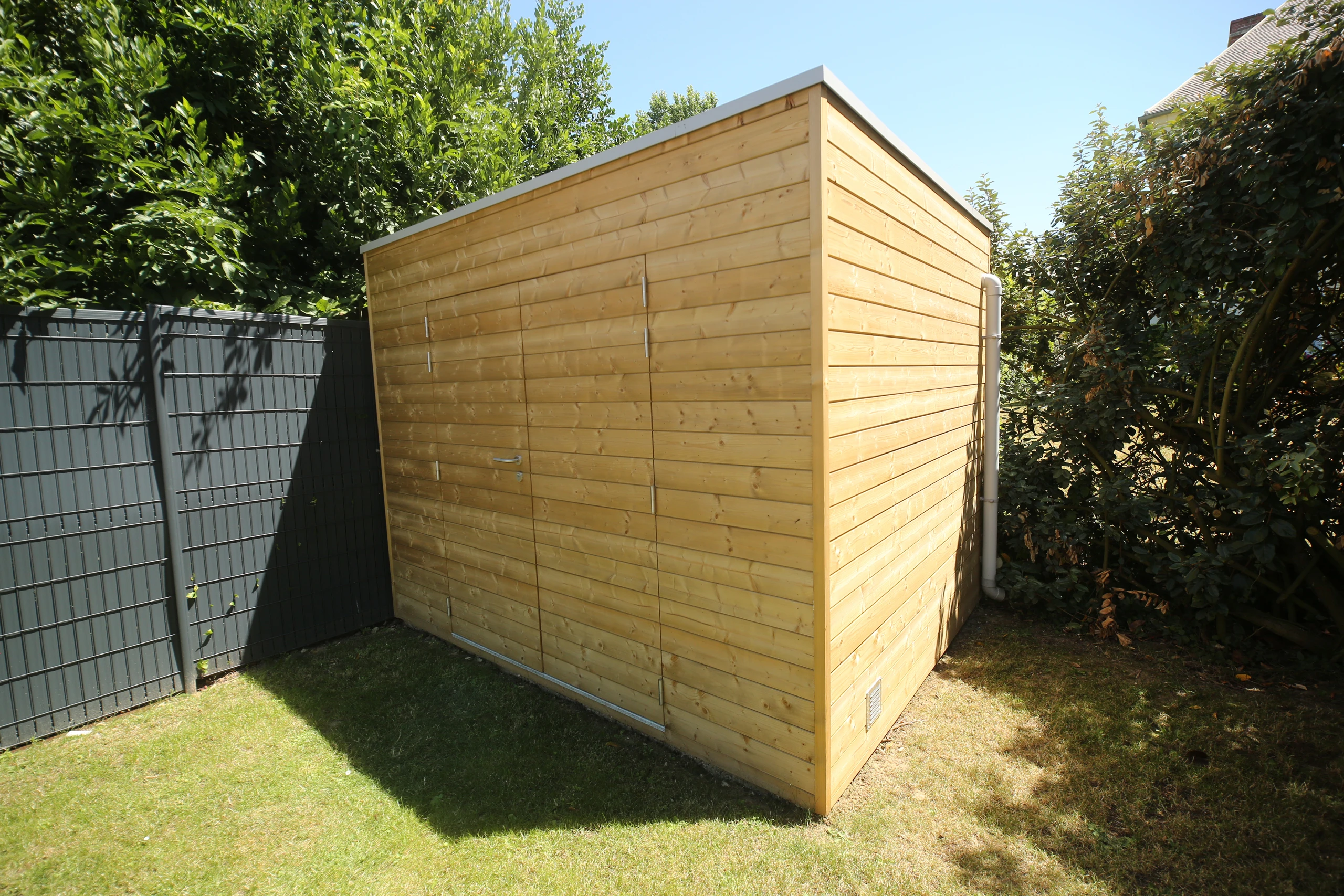 Abri de jardin toit plat en bois clair avec double porte, pose soignée à Lacroix-Saint-Ouen — Colver
