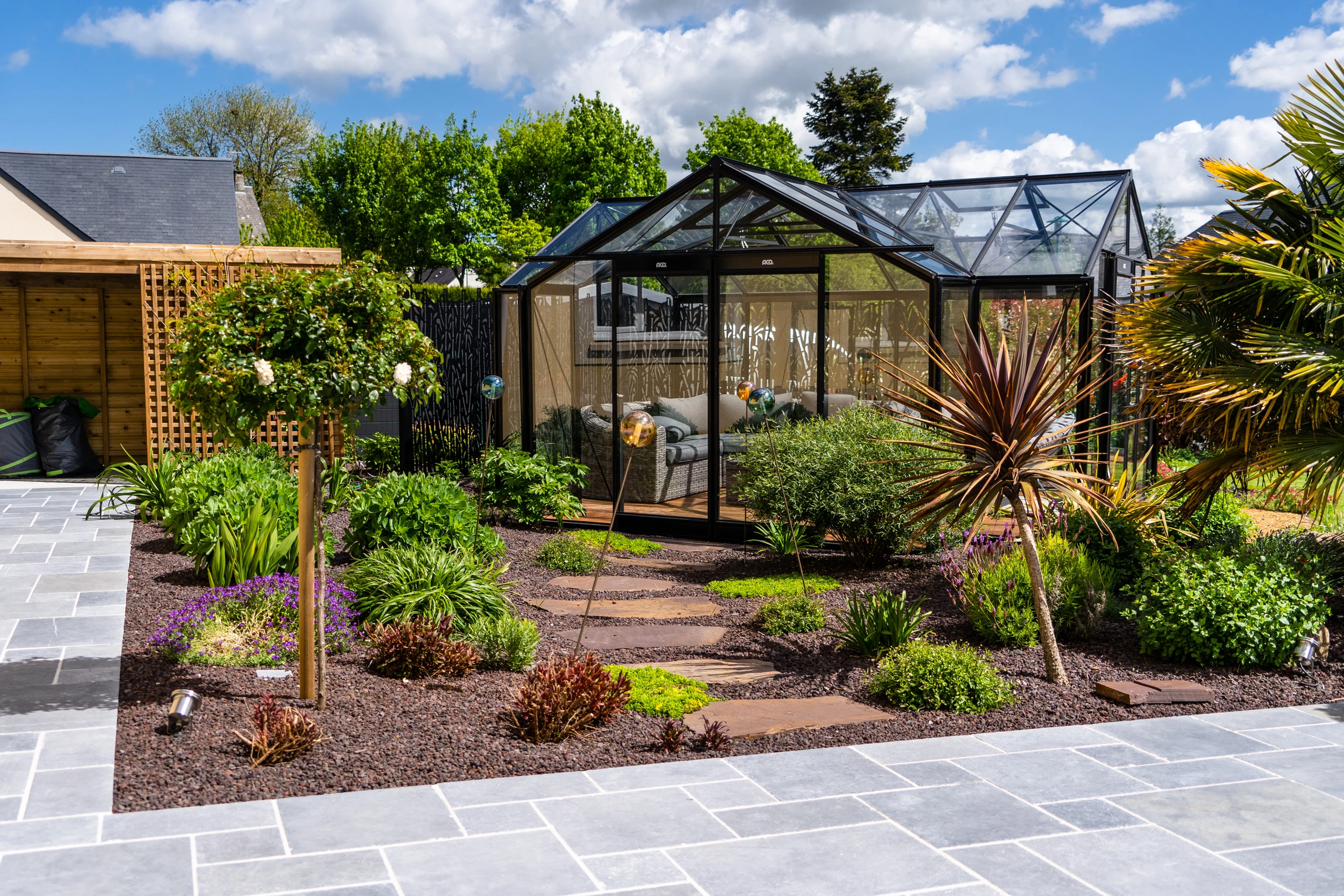 Serre jardin d'hiver haut de gamme aménagée en salon avec mobilier lounge et massifs plantés à Ribécourt-Dreslincourt — Colver