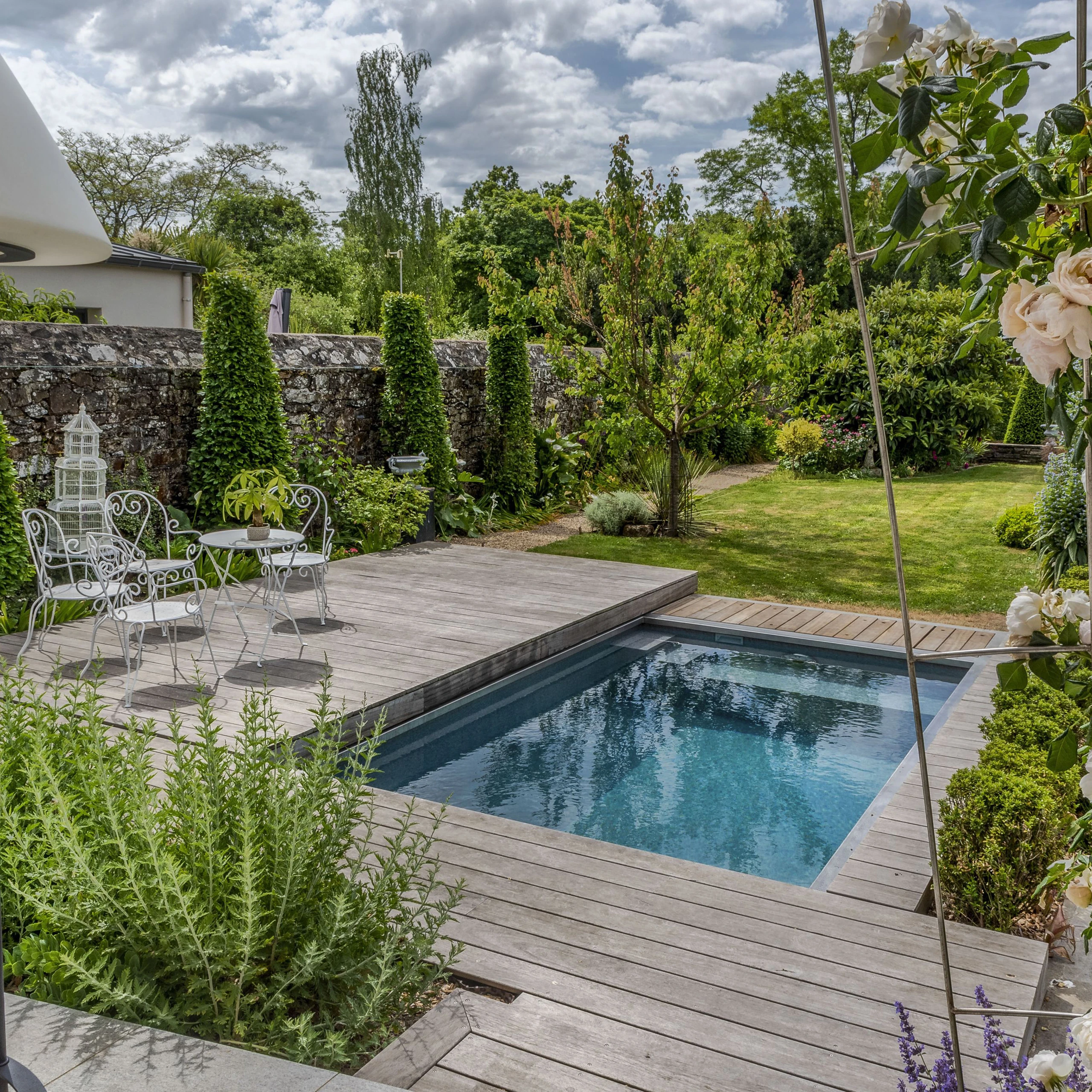 Spa de nage avec terrasse bois grisé et salon en fer forgé blanc, jardin romantique mur en pierre à Thourotte — Colver