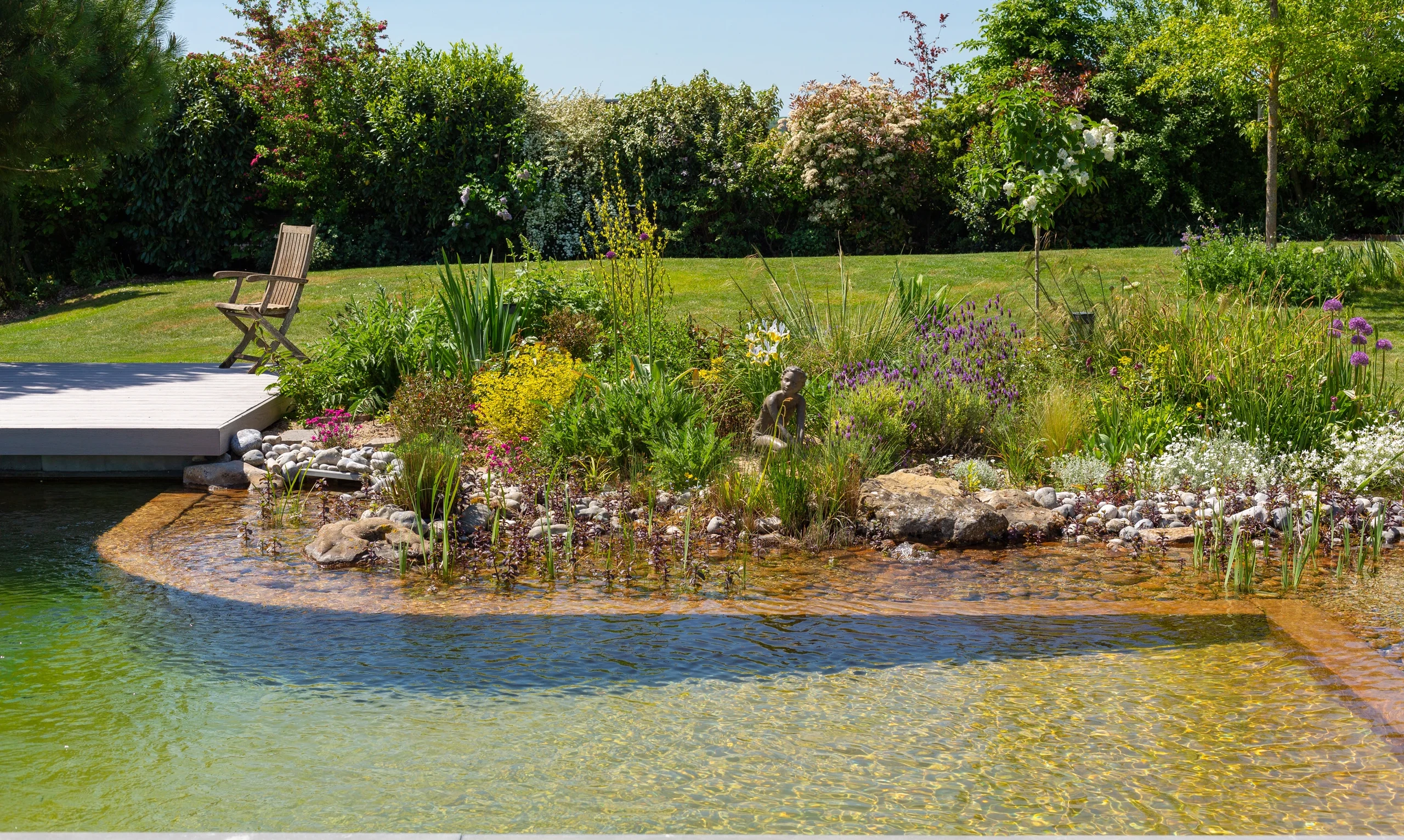 Bassin naturel avec zone plantée fleurie, terrasse composite gris et statue — Soissons, Aisne — Colver